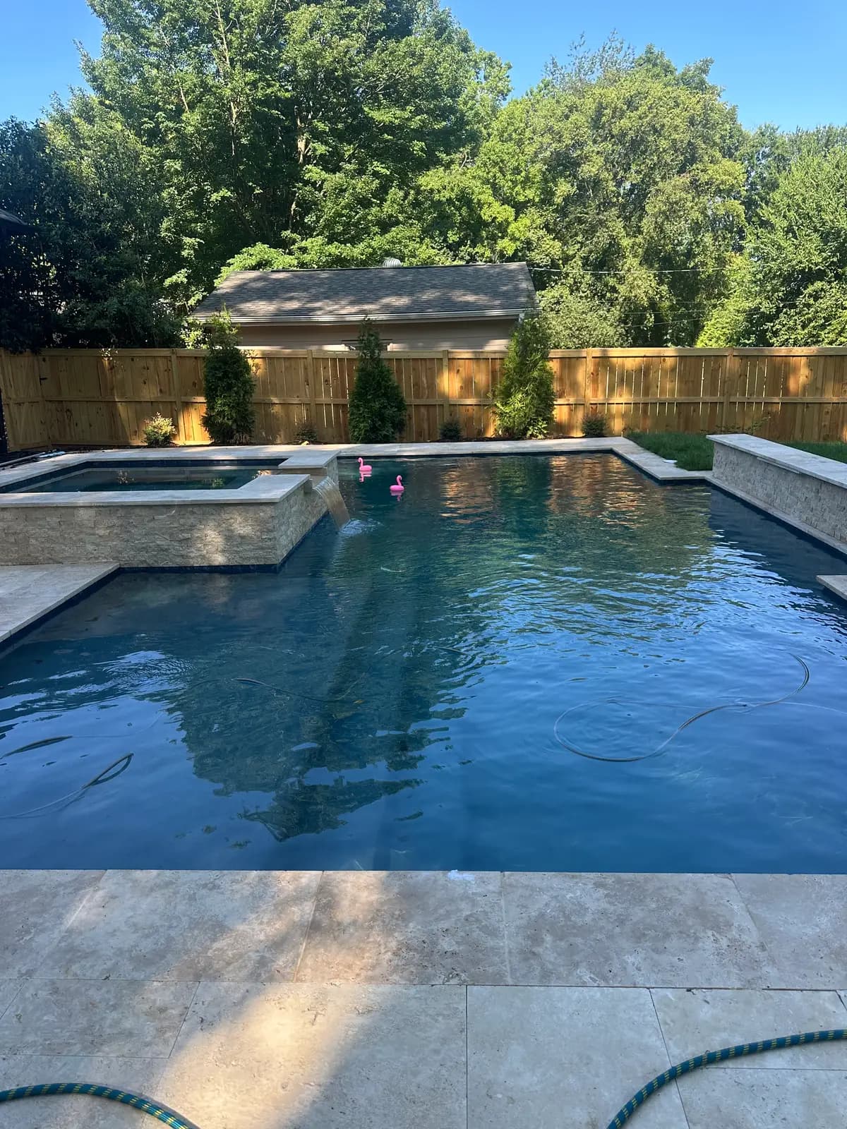 Finished pool and spa with a travertine deck on a Charlotte builder project